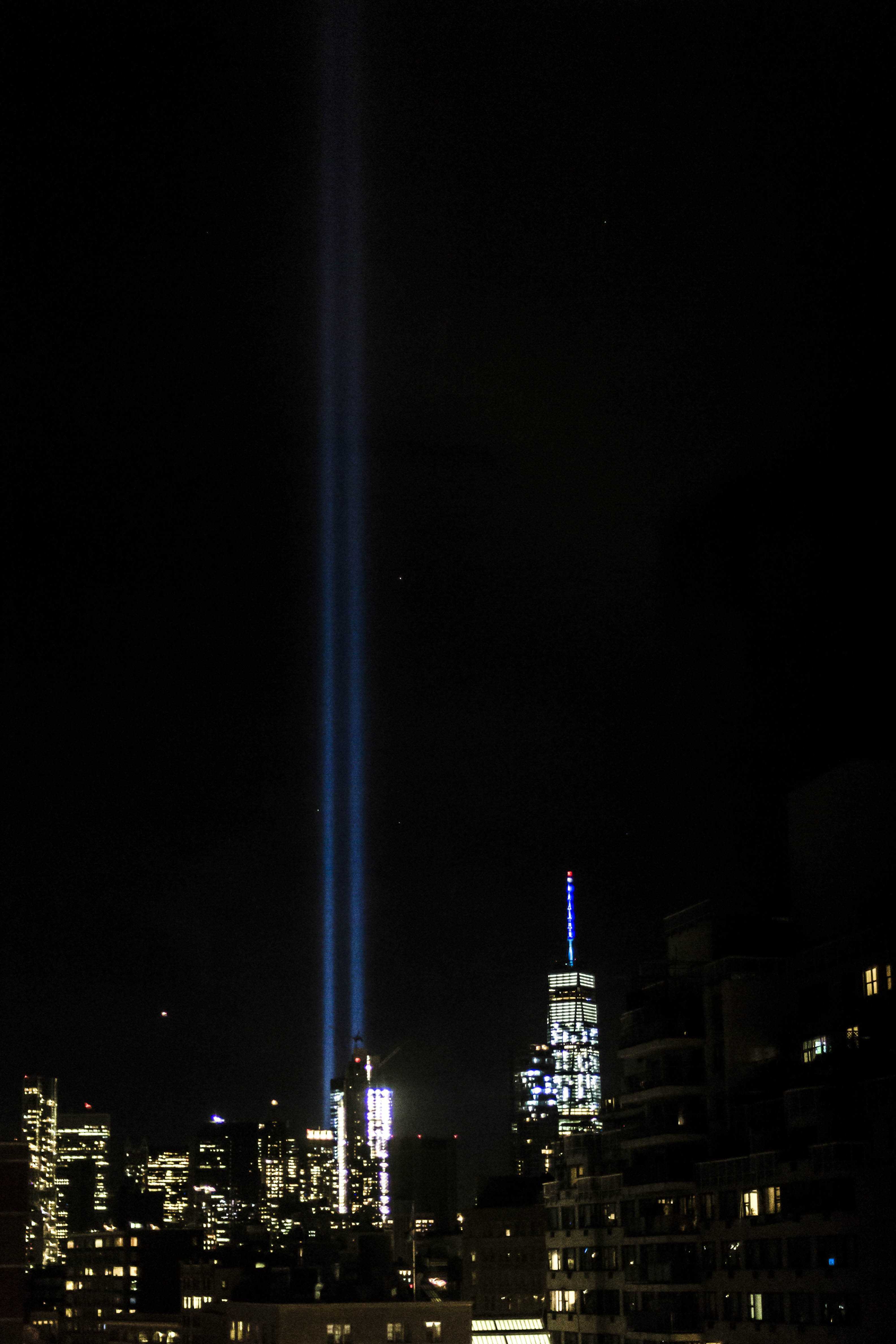 Two bright beams shine from the 9/11 Memorial’s reflecting pools, marking the sky with a ghost of where the Twin Towers once stood.