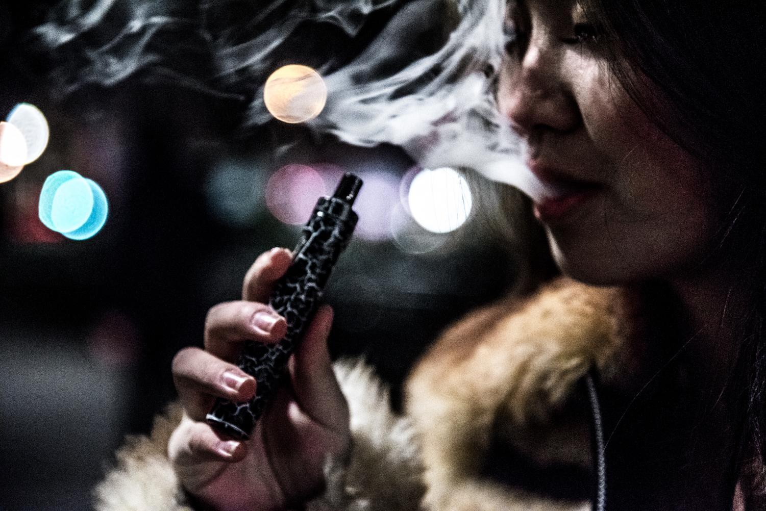 A first-year vapes in Union Square at night. She only started vaping since being at NYU, primarily doing so on nights out.