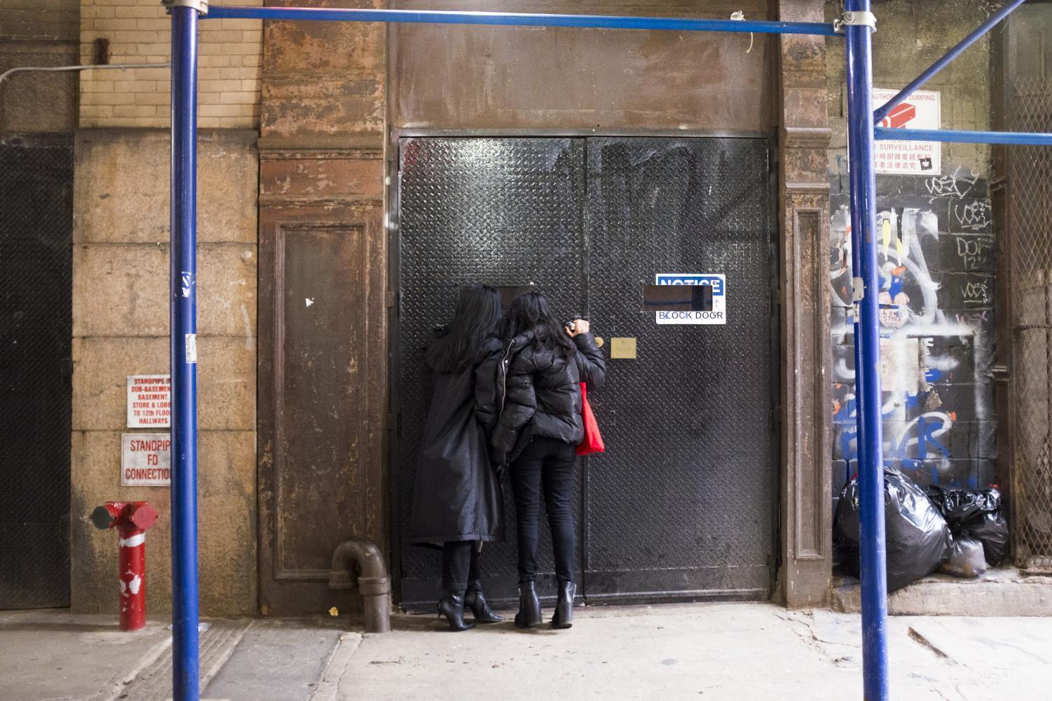 Two visitors peek inside Mmuseumm, located on Cortlandt Alley. Even when the museum is closed, visitors can call a toll-free number to hear about the objects, or look inside the building’s windows.